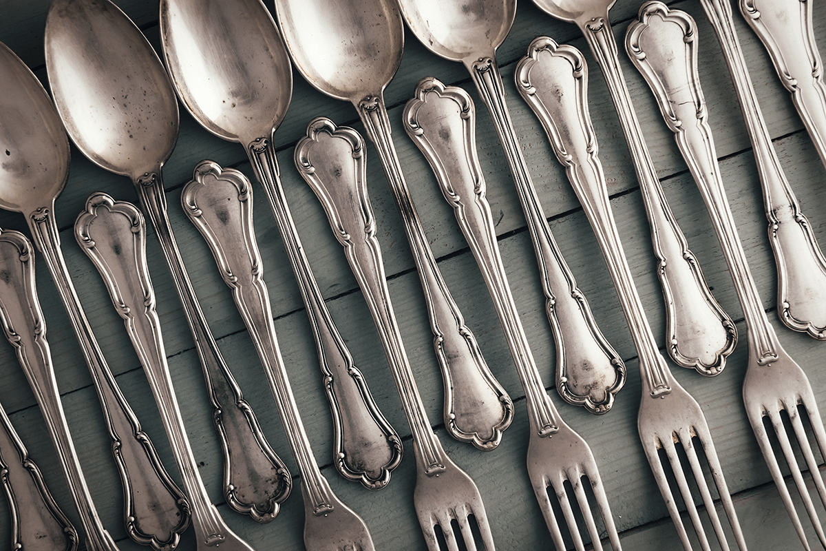 a bunch of silver spoons lined up on a table
